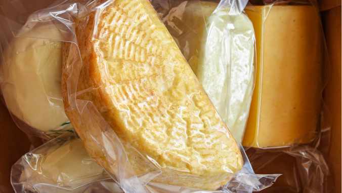 A pile of different types of packaged cheese