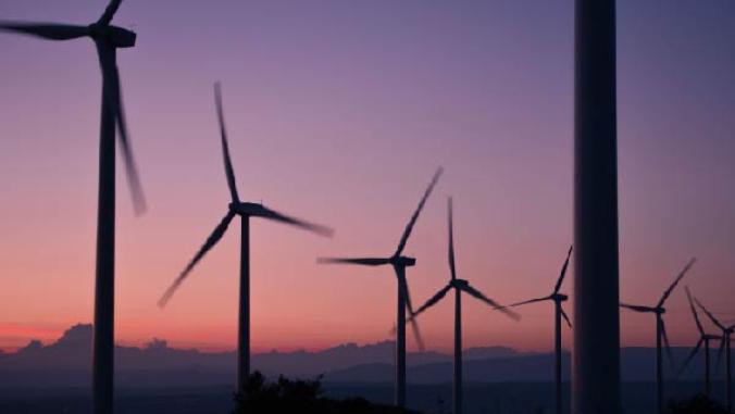 a group of wind turbines spinning during a pink and blue sunrise or sunset