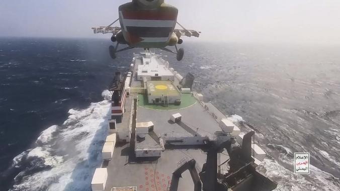 Helicopter hovering over and approaching cargo ship in the Red Sea