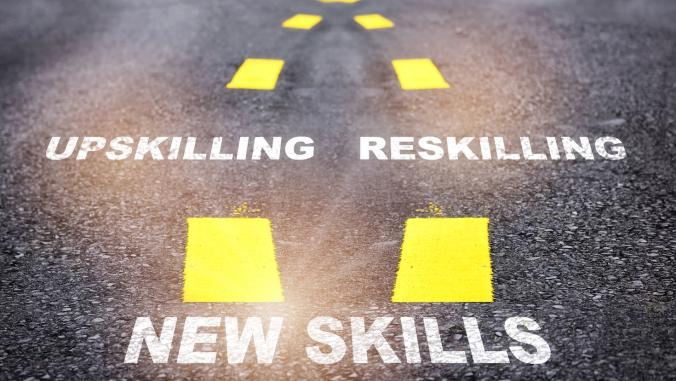 New skills, reskilling and upskilling written on asphalt road
